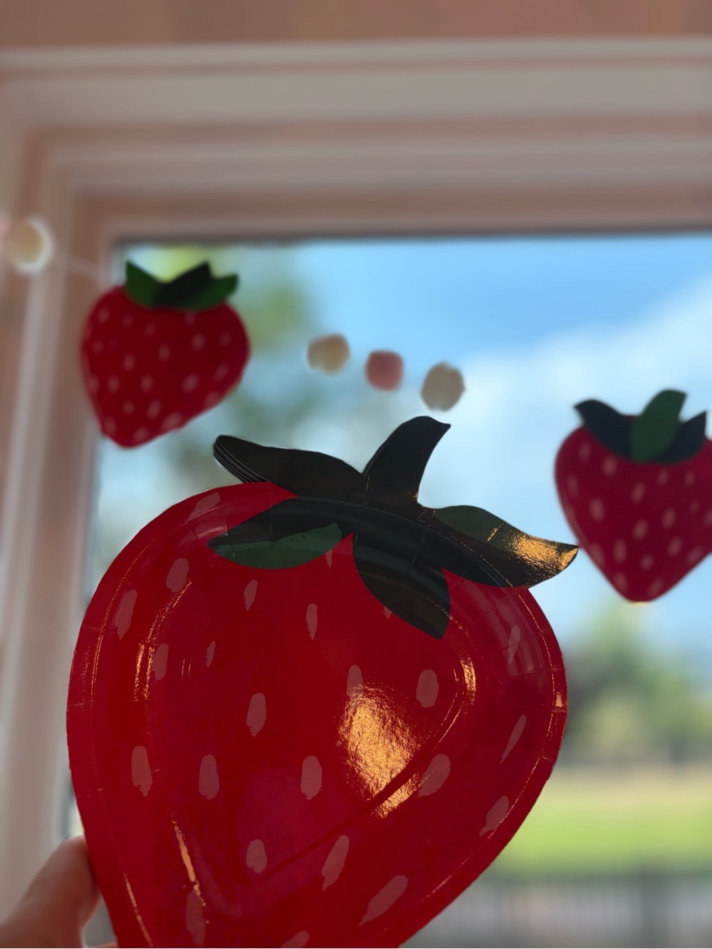 Strawberry paper party plates with matching Strawberry and pom pom garland!